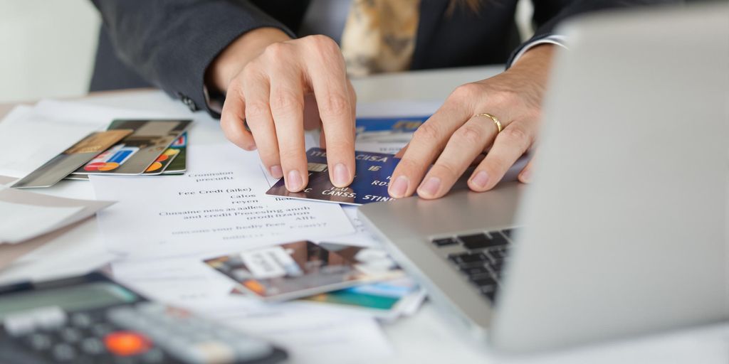Business owner managing credit cards and finances at desk.
